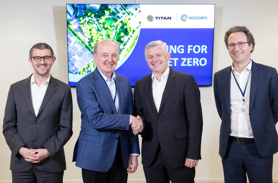 4 men smiling for a photo, two of them are shaking hands.